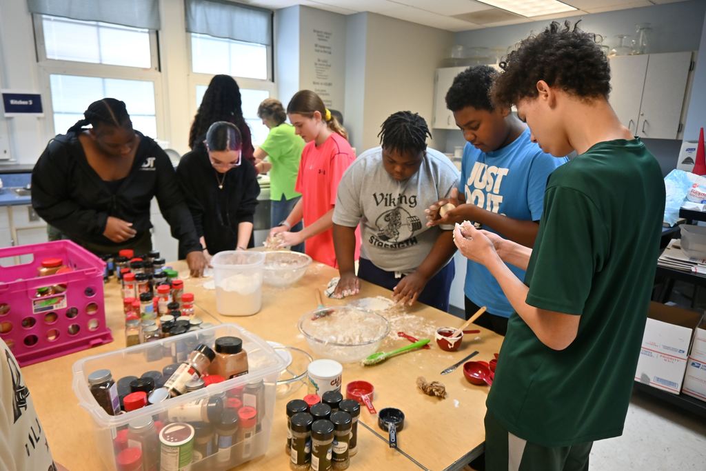 Students make balls of dough they flatten out to make pita bread.