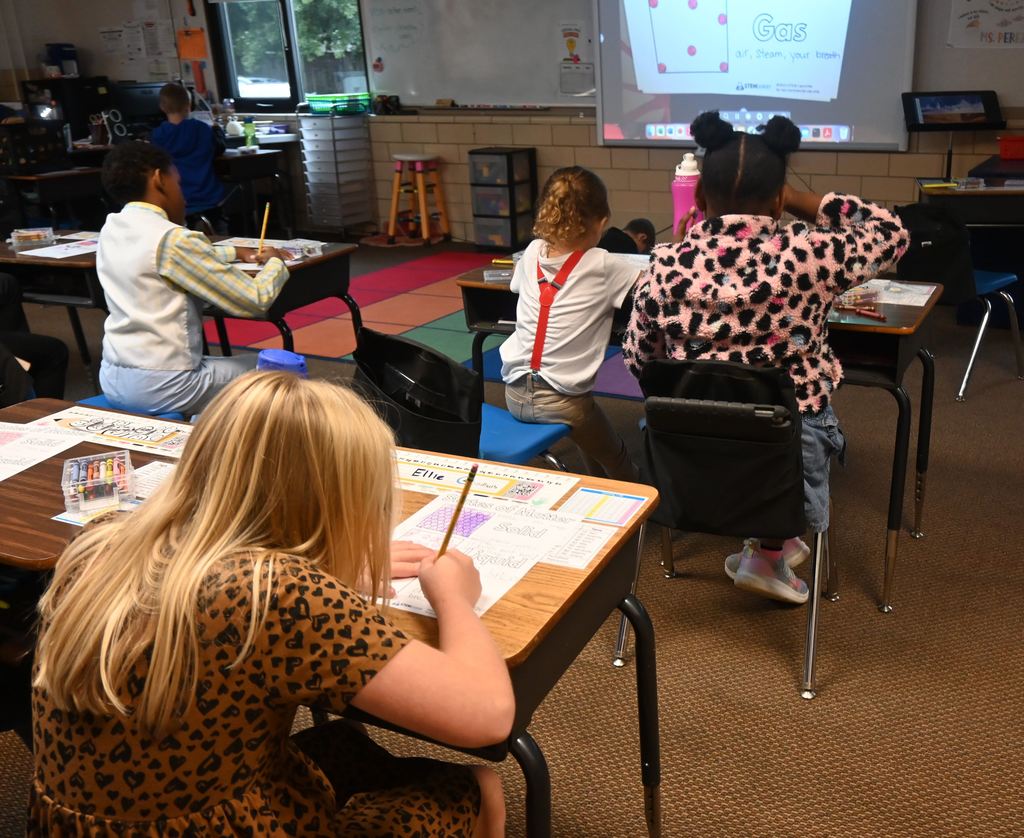 Students write information from the screen on their sheets about solids, liquids and gases.