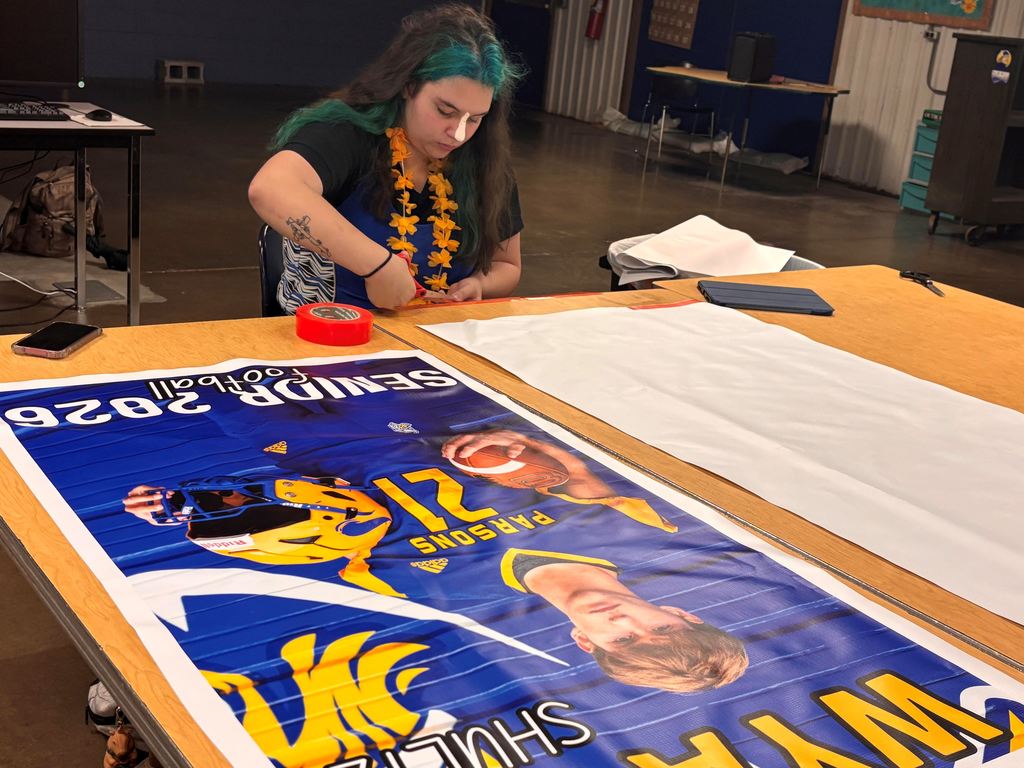 A student tapes all the raw edges of the banners to make neat seams.