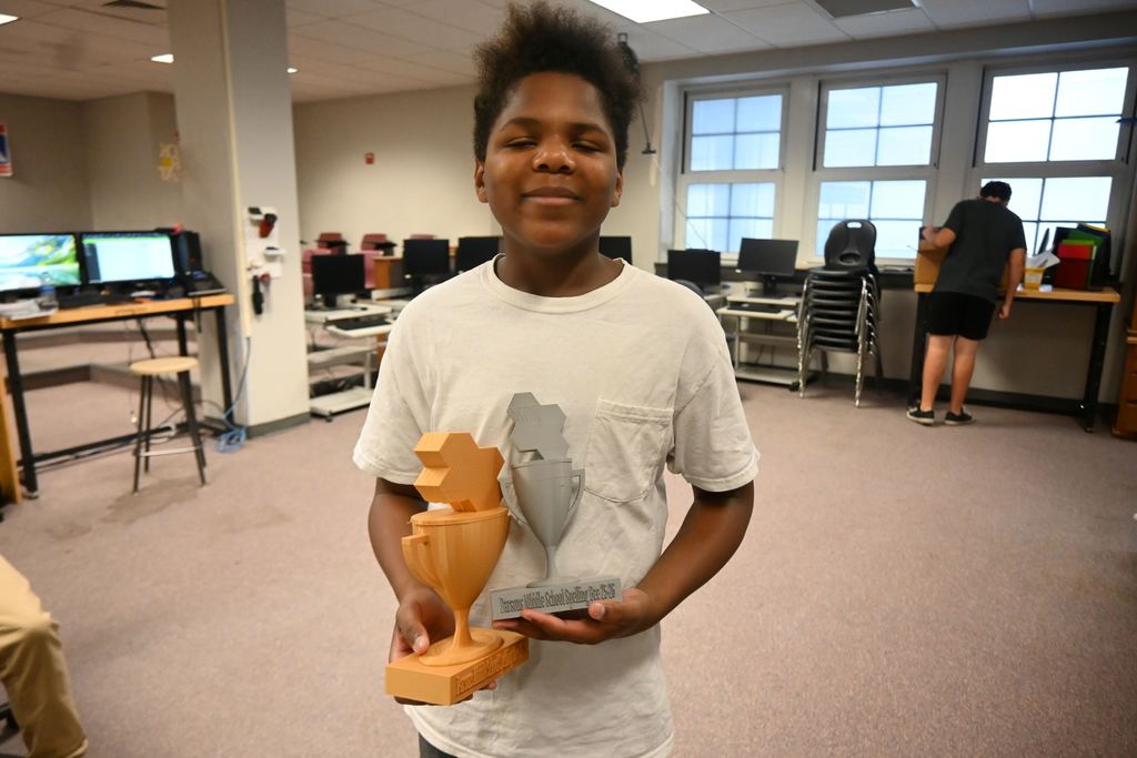 Kevion holds the Spelling Bee Trophies he designed