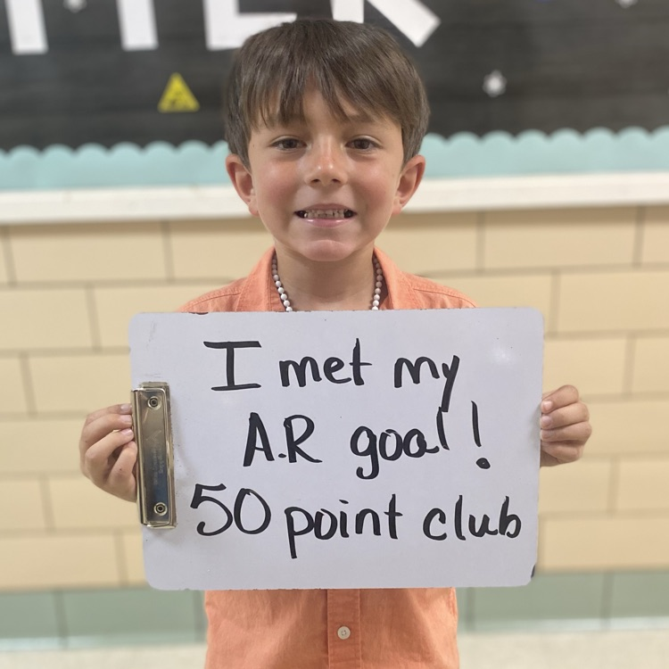student holding a sign that denotes he has met his AR goal