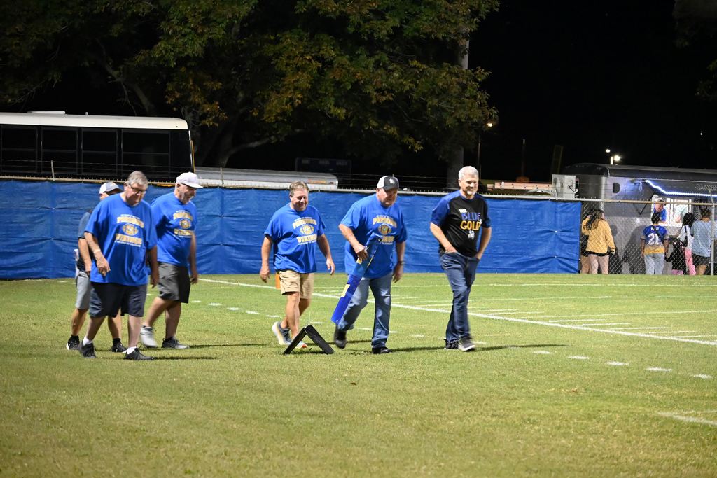 Members of the 1975 PHS football team gather on the field with former line coach Harley Turner.
