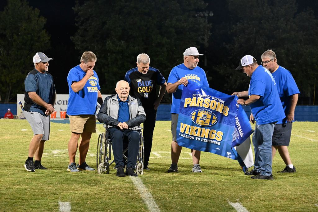 Members of the 1975 PHS football team gather on the field with former line coach Harley Turner.