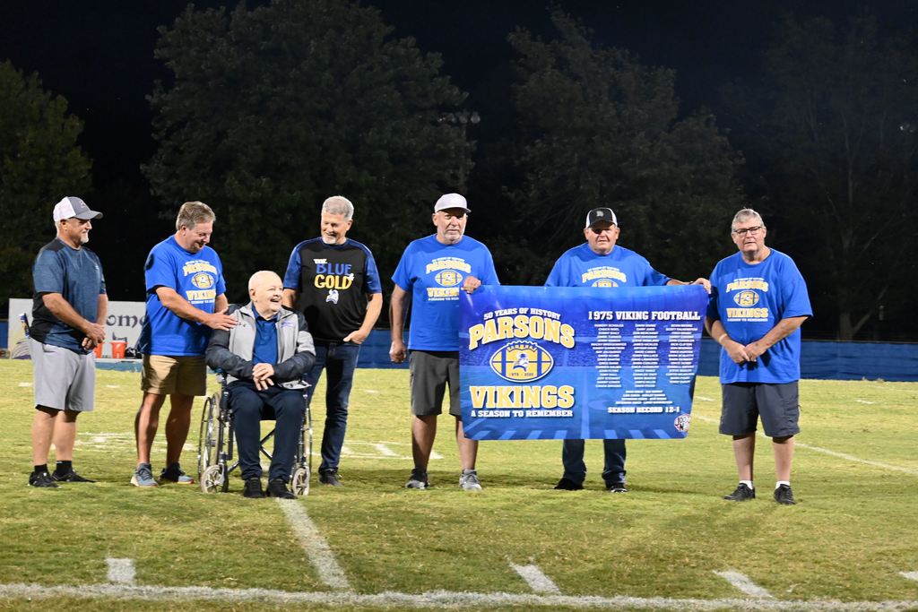 Members oif the 1975 PHS football team gather on the field with former line coach Harley Turner.
