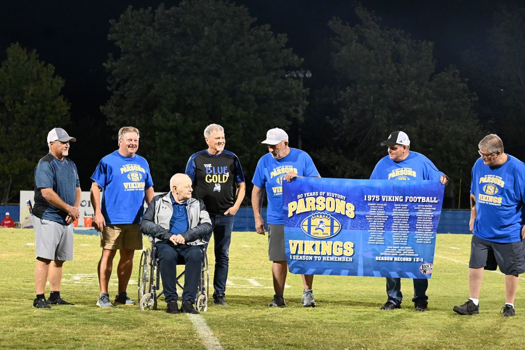 Members of the 1975 PHS football team gather on the field with former line coach Harley Turner.