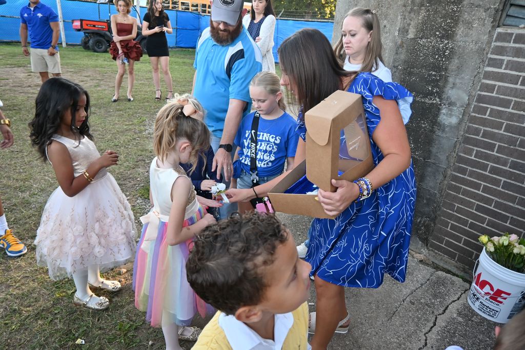 Kylie Lucas places wrist corsages on the little girls.