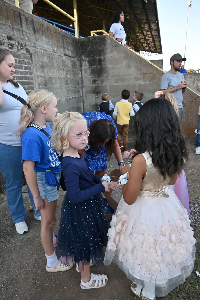 Two little girls show each other their wrist corsages.