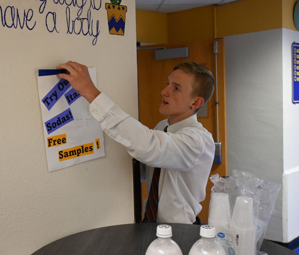 A student hangs a flyer about free taste testing.