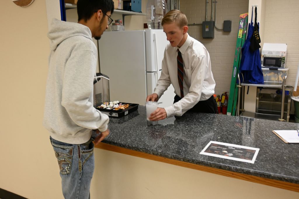 One of McClean's students serves another student his drink.