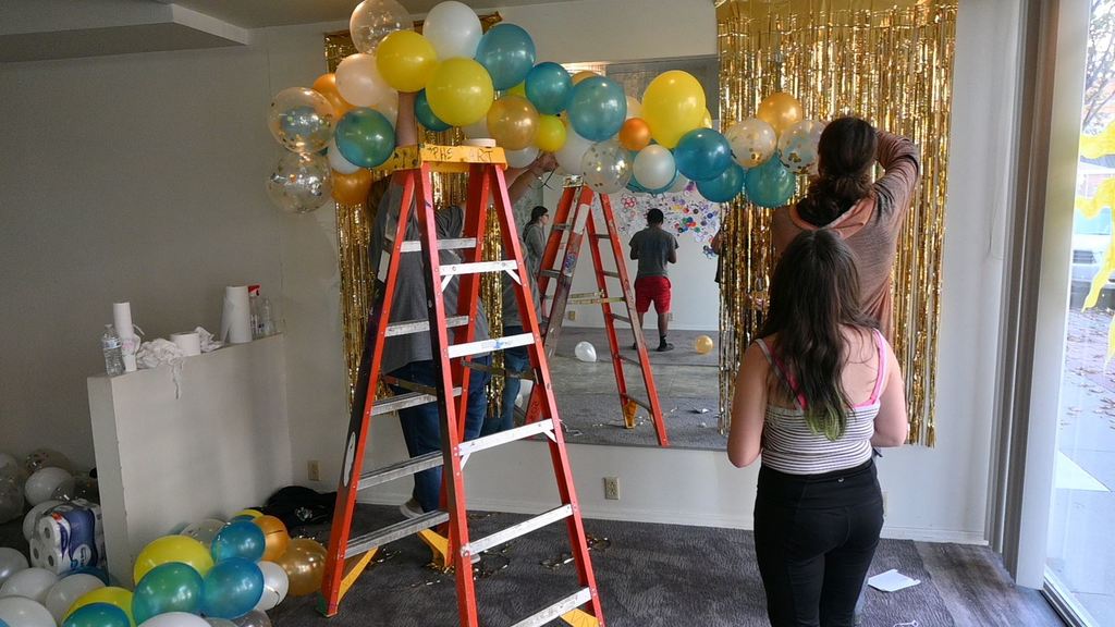 Ms. Vincent and students hang balloons to decorate the exhibit area.