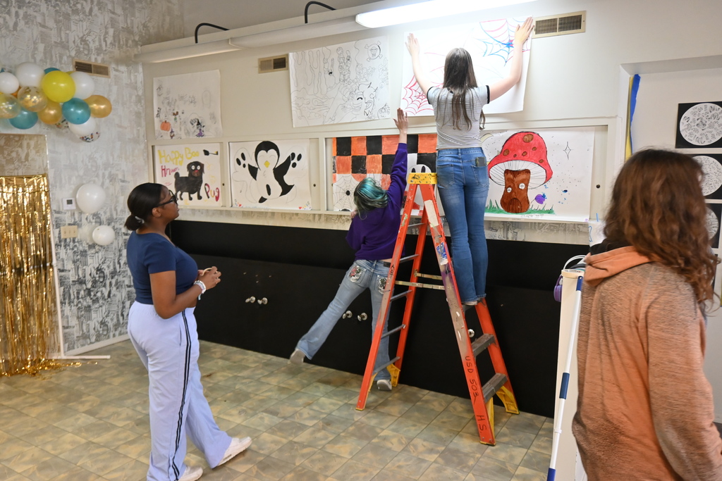 PHS Students hang posters made by middle school students.