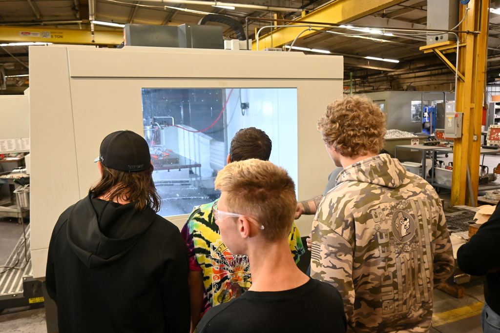 Students watch as a  laser water jet cuts parts.