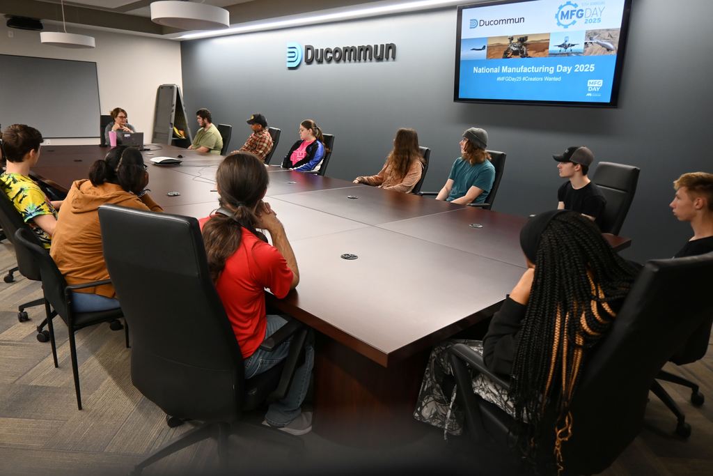 Students watch a slide show about Ducommun in the conference room.
