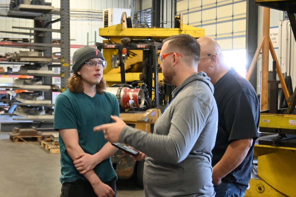 A student asks a question of two employees leading the tour.