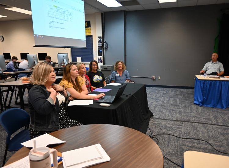 Instructional coaches speak to the board. 