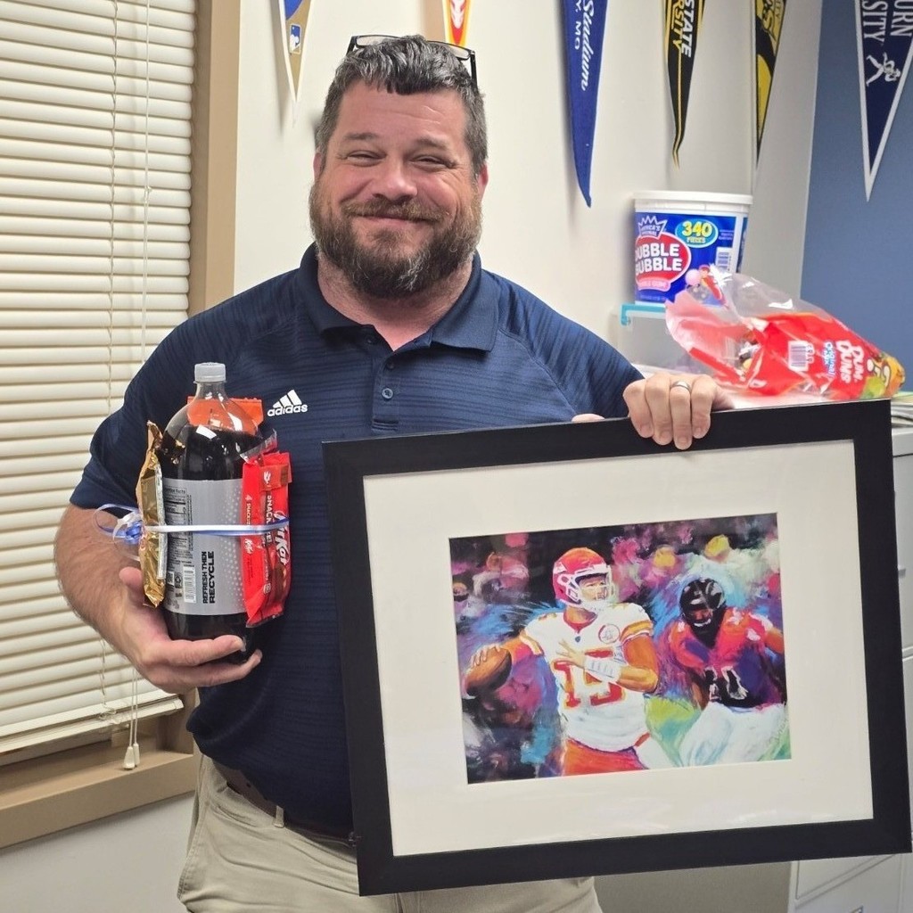 a man holding snacks and a framed Chiefs picture