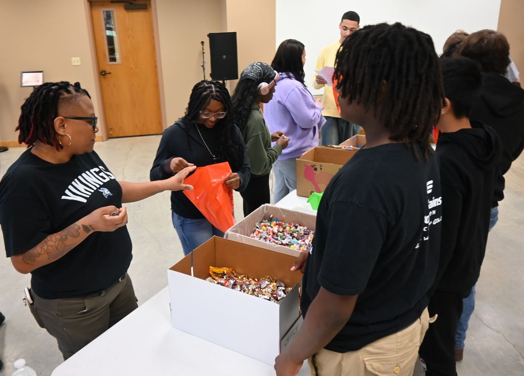 Mrs. Mayhue helps put candy in bags.