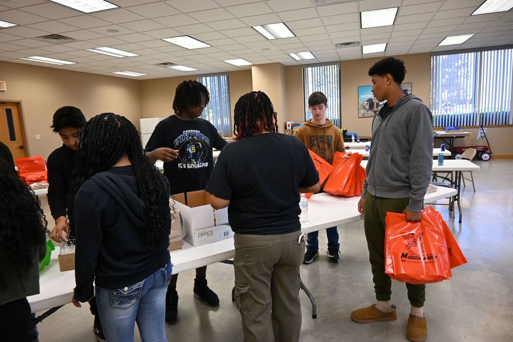 Students stuff goodies in bags for children who attend the Monster March.
