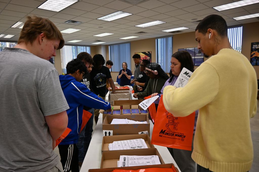 Students stuff goodies in bags for children who attend the Monster March.