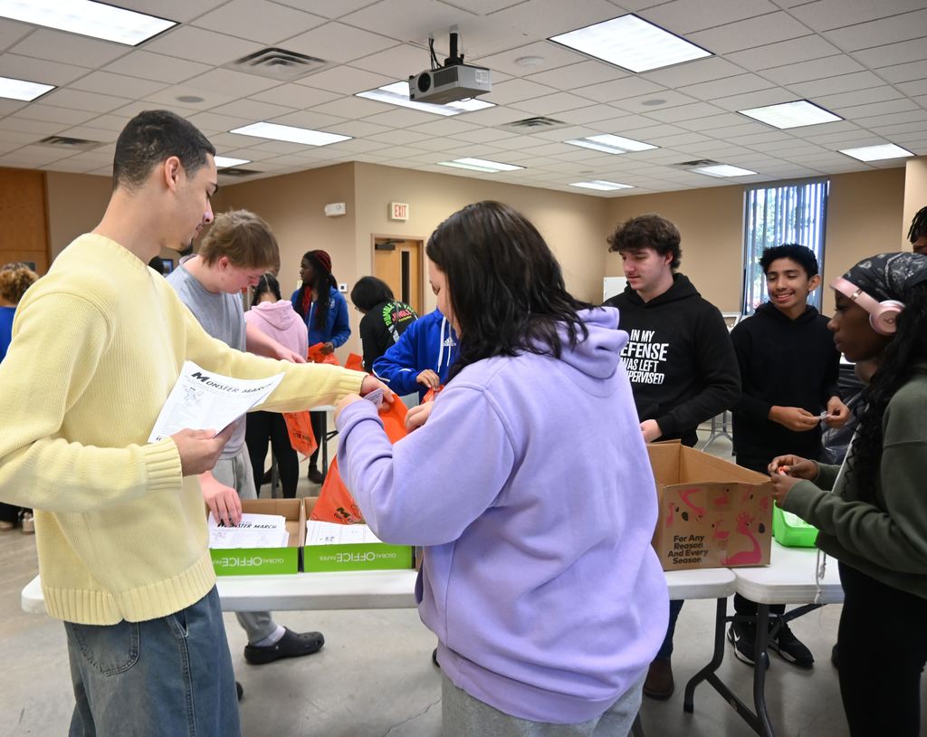 Students stuff goodies in bags for children who attend the Monster March.