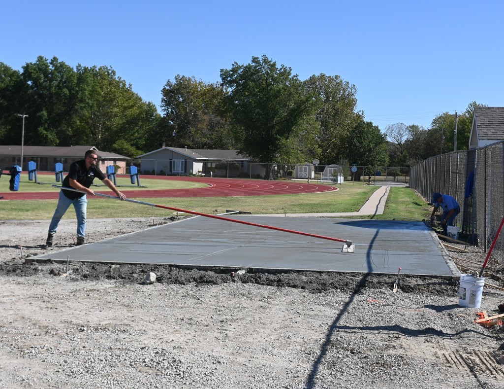 Maintenance Director Keaton Nolting smooths concrete with Tim Bowman.