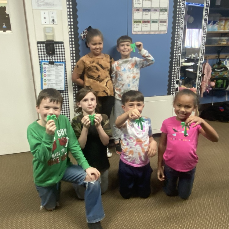 students posing and holding 3-D printed palm trees