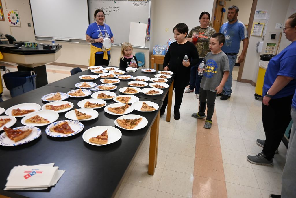 A family stops by the art room to grab some pizza.