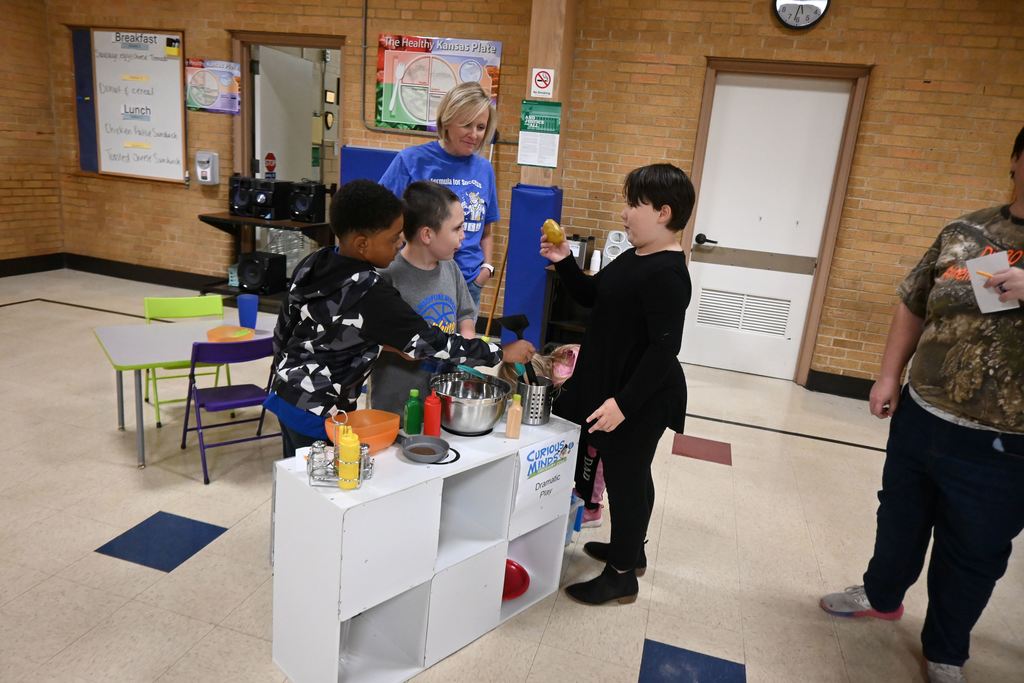 Students play in a pretend kitchen, whipping up some dinner.