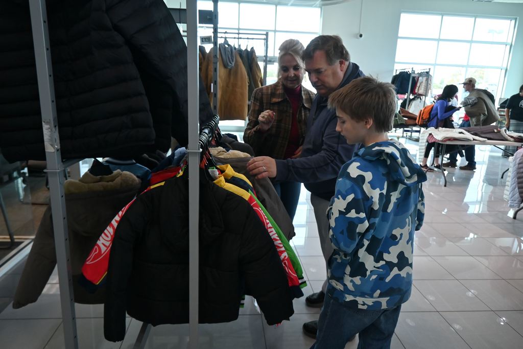 Tom Davis helps a boy find a coat.