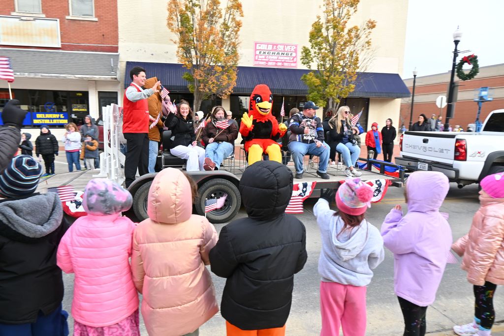 Children wave at LCC employees and veterans riding on a trailer in the parade.