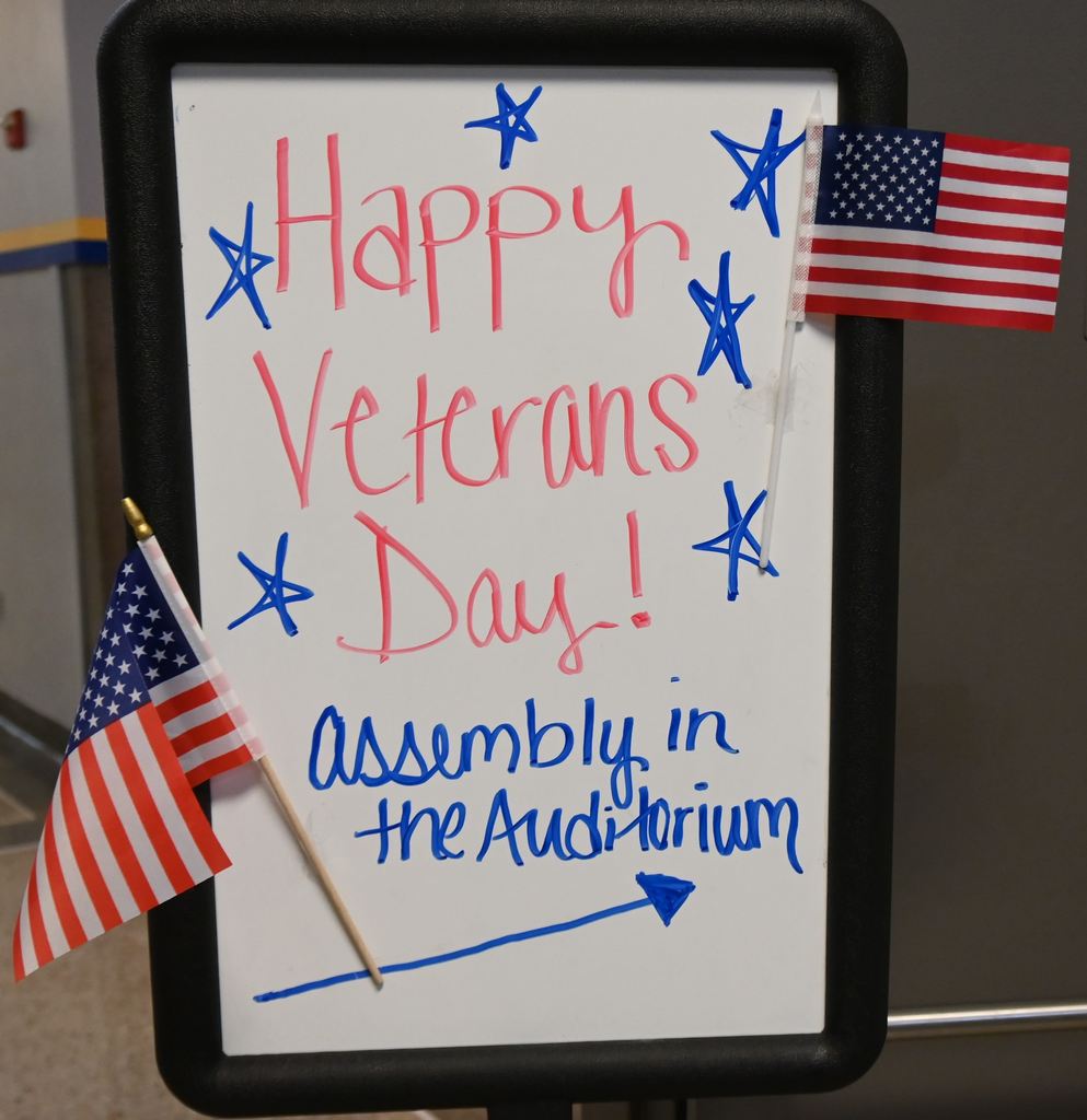 A sign tells people Happy Veterans Day and directs them to the auditorium.