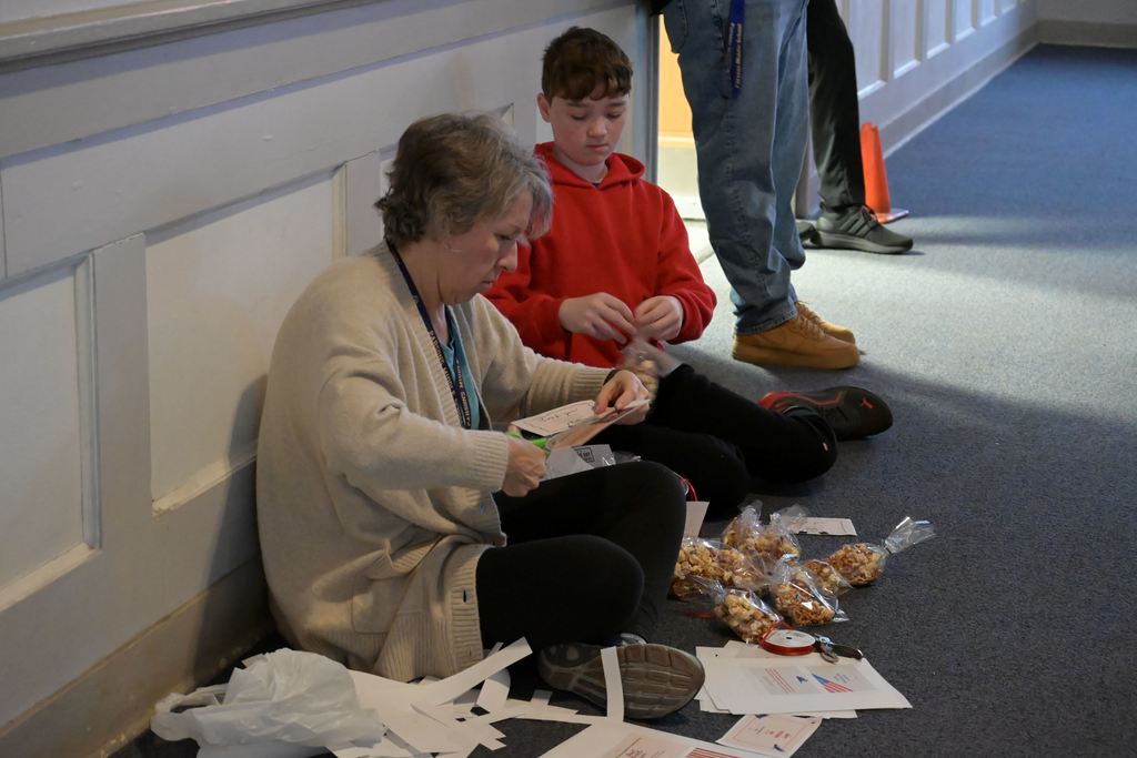 Barbara McCoy and student Logan Downey work on treat bags. 
