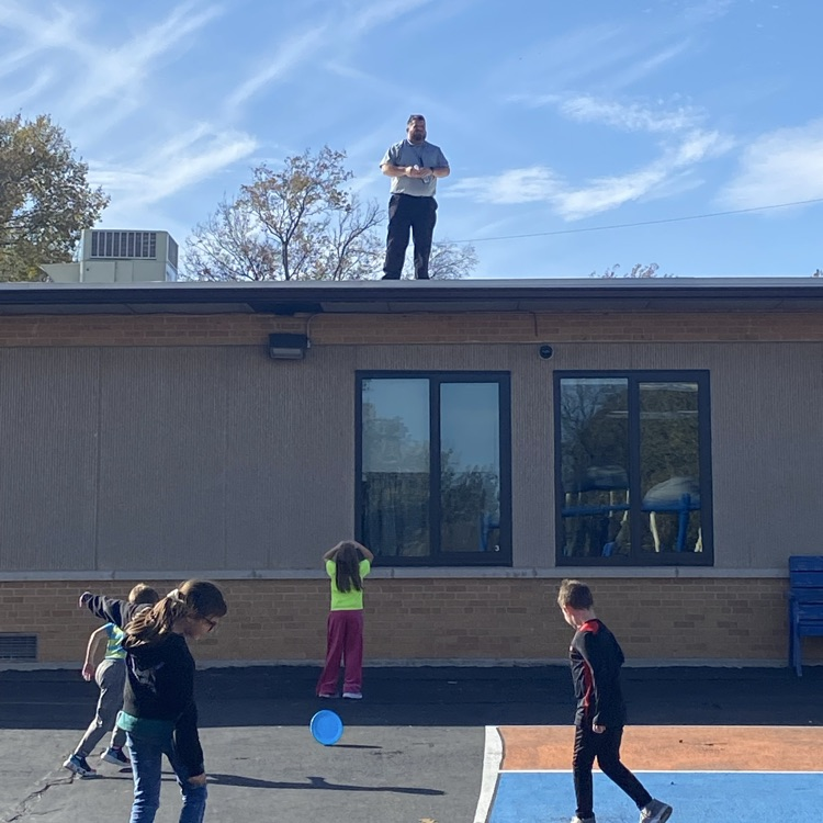 man on the roof of the school retrieving a frisbee