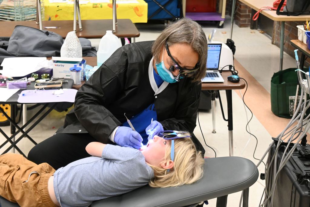 Someone from CHC Dental Clinic, cleans a boy's teeth.