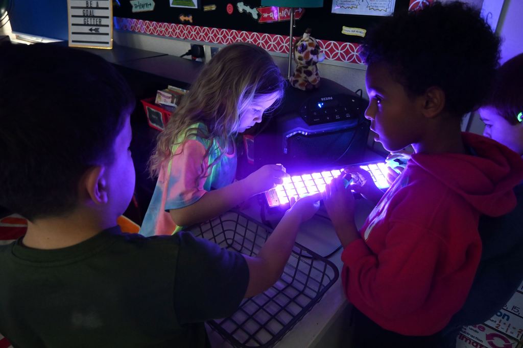 Students test their spiiners under black light.
