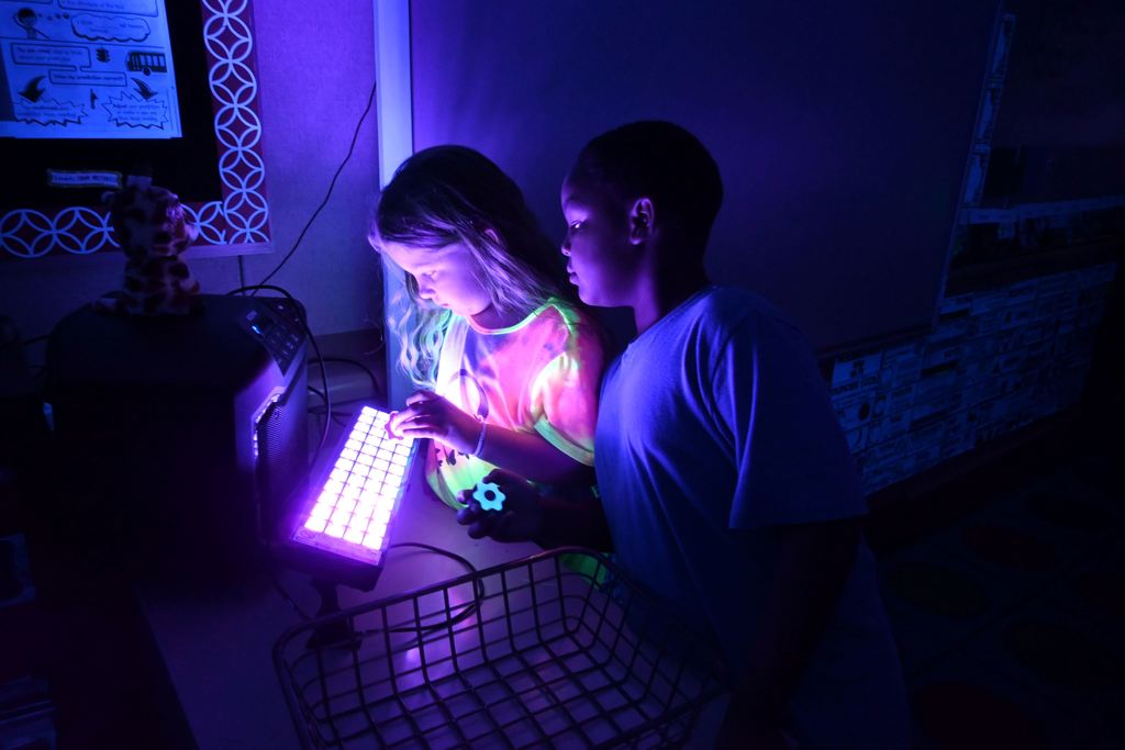 Students test their fidget spinners in black light.
