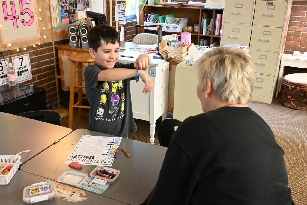 A boy shows his bracelet to a friend from Presby.
