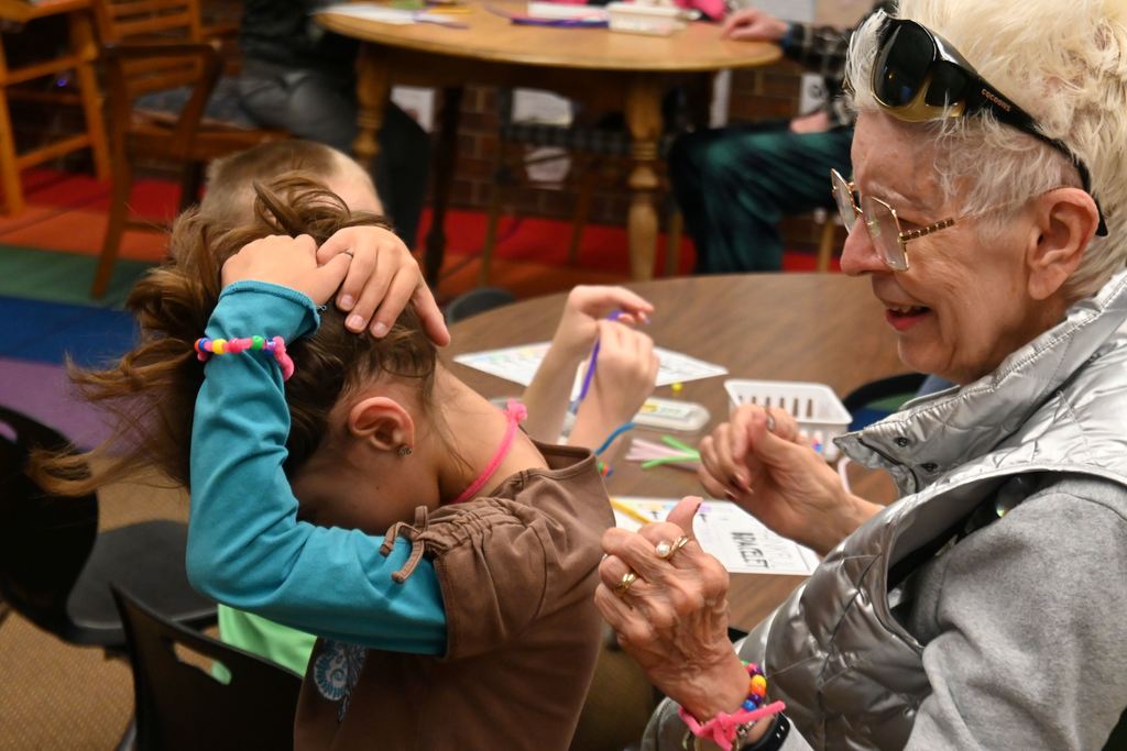 A little girls gets help from her Presby friend to fix her necklace.