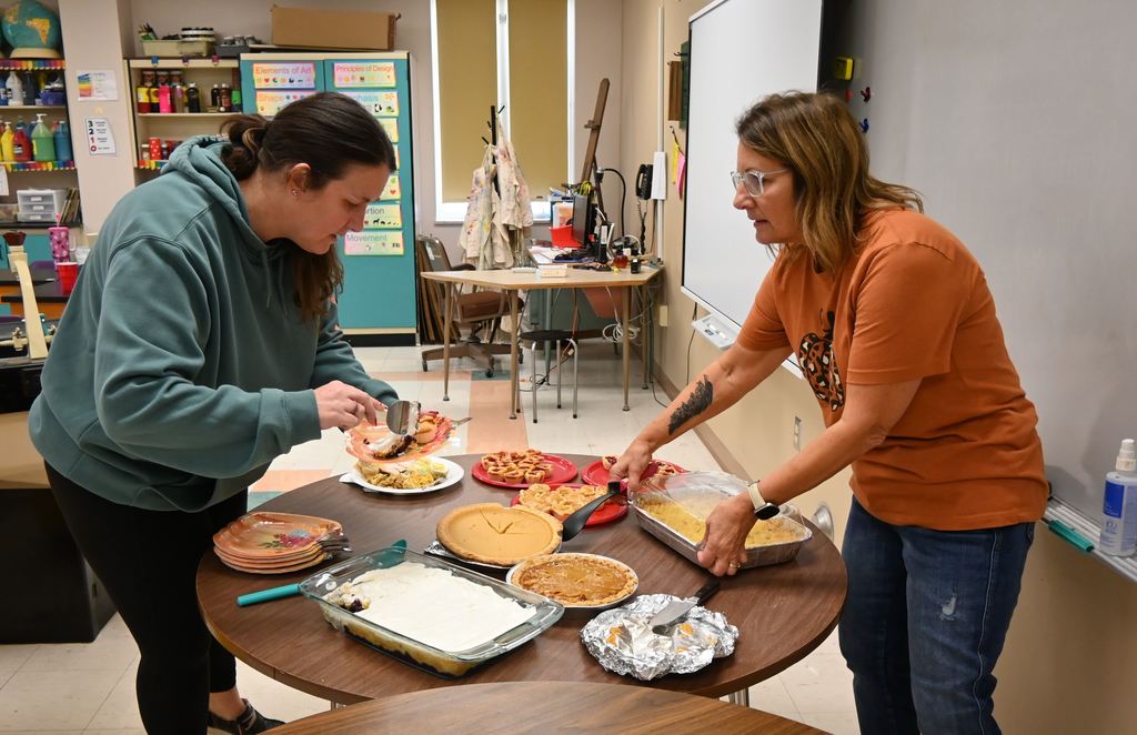 Two staff members uncover desserts.