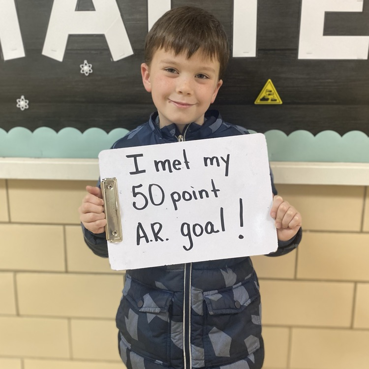 student holding a sign saying that they met their 50 point AR goal