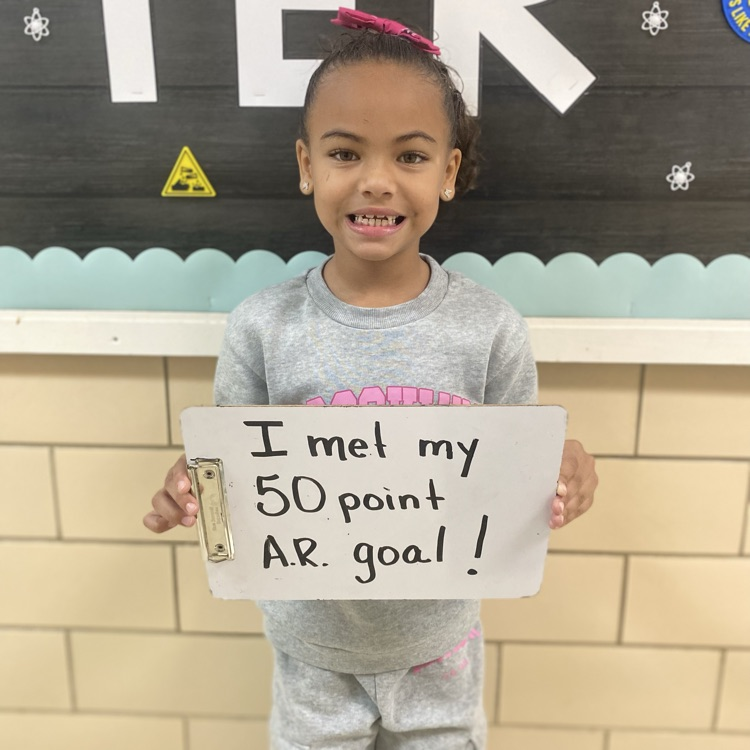 student holding a sign saying that they met their 50 point AR goal