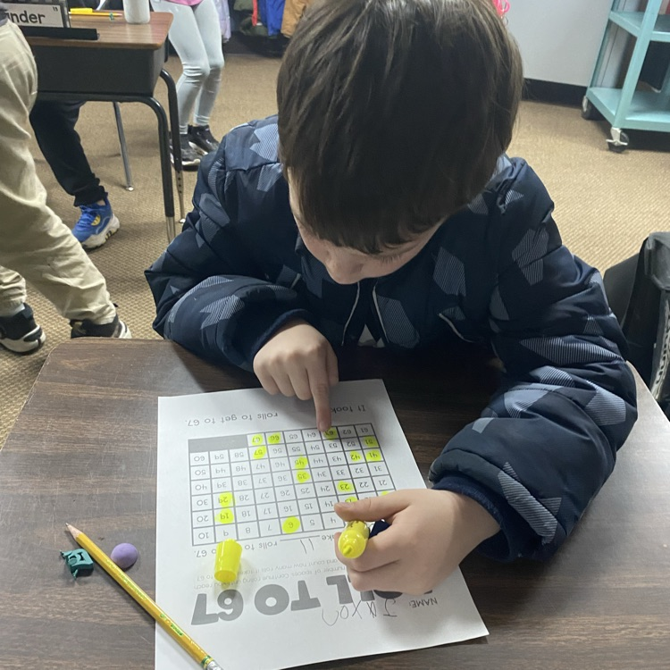 student at a desk rolling dice to 67