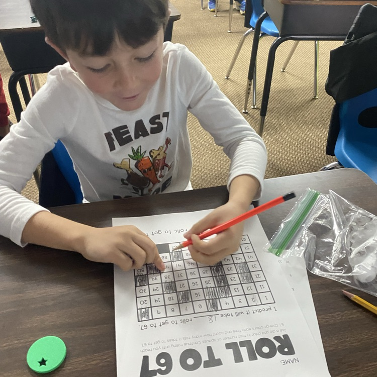 student at a desk rolling dice to 67