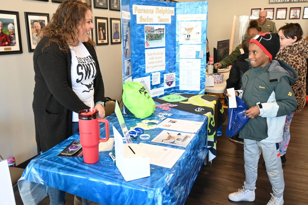 A boy visits with a representative of the Dolphins Swim Team.
