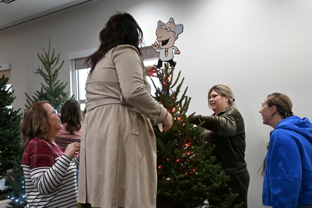 Staff place the tree topper and adjust the lights.