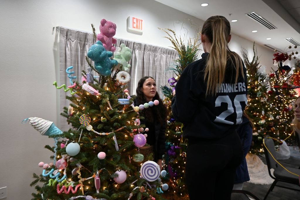 FCCLA students decorate a tree for Stella Wells with large candy replicas like gummy bears and lollipops.