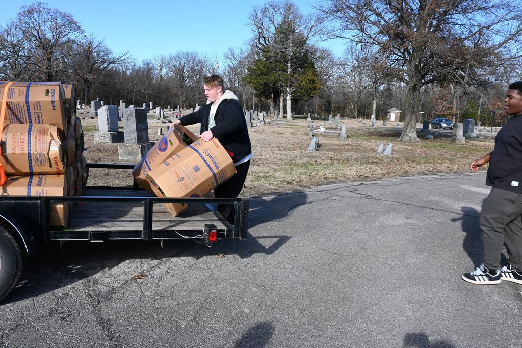Athletes unload the boxes of wreaths from the trailer.