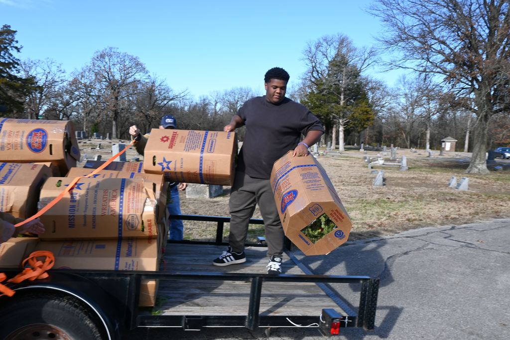 Athletes unload the boxes of wreaths from the trailer.