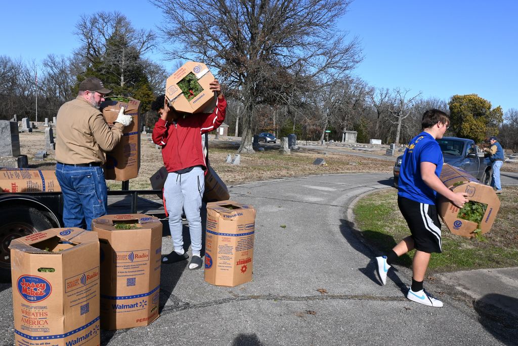 Athletes unload the boxes of wreaths from the trailer.