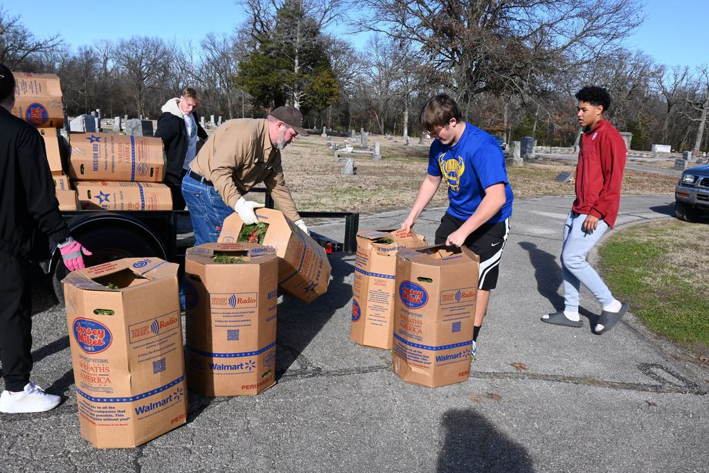 Athletes unload the boxes of wreaths from the trailer.